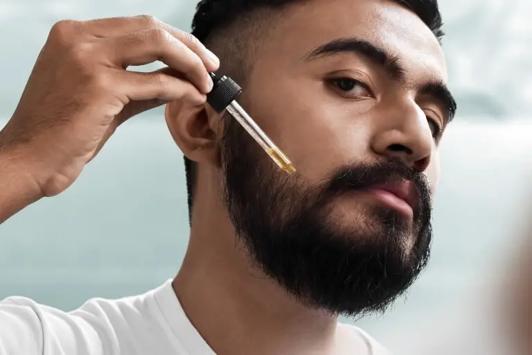 Man som applicerar skäggolja i sitt skägg